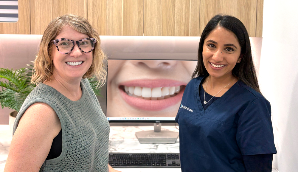 Patient and dentist standing by computer, looking at the patient's dental photo on the screen.
